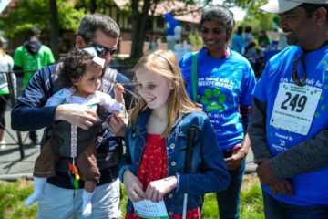At the Walk for INDEPENDENCE, a baby grabs a laughing girl's hair while two onlookers smile in the background.
