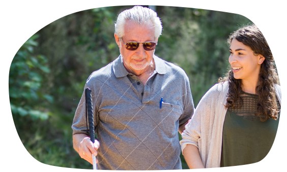 An older gentleman gets sighted guide from a younger woman while crossing train tracks.