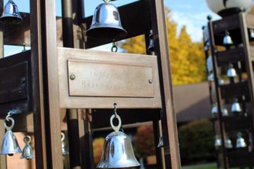A close-up of a bell hanging from the memorial bell towers on campus.