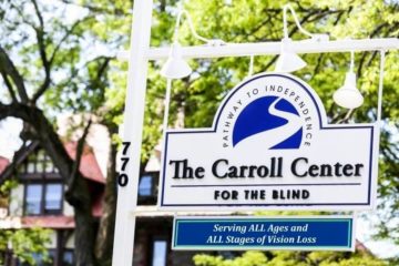 A large sign at base of the Carroll Center for the Blind's driveway features the Center's logo and tagline, "Serving ALL ages and ALL stages of vision loss."
