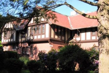 The West Entrance of the Carroll Center for the Blind's main building, a large Tudor-style brick structure with beautiful landscaping out front.