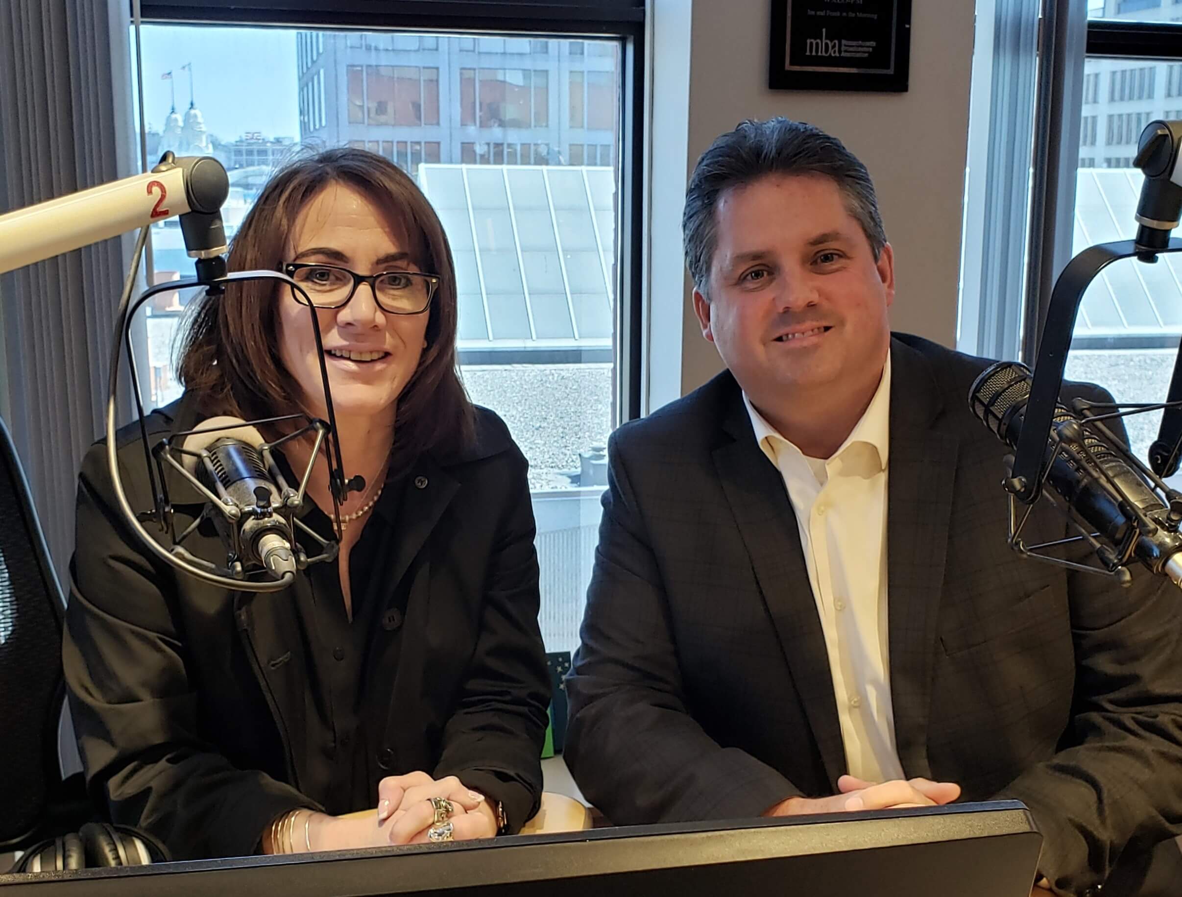 Two people sit in a recording studio. Vicki Green, host of Community Conversations on WXLO 104.5FM is on the left. Carroll Center for the Blind President and CEO, Greg Donnelly, is on the right.