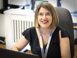 Kate Katulak, a 2019 Carroll Society Award inductee, smiles while working on a laptop at her desk at Perkins.