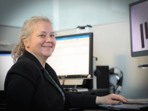 Pauline Dowell, a 2019 Carroll Society Award inductee, smiles while using a desktop video magnifier at her work station in the MIT Human Resource department.