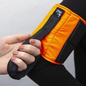 An orange Ramble Tag is worn on a guide's arm. A person's hand holds onto the black handle.