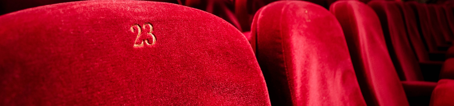 Close-up of a row of red velvet seats at a theater.