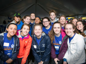 14 female high school volunteers pose together wearing matching blue shirts at the Walk for INDEPENDENCE.