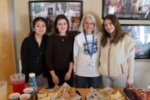 Group photo of four volunteers, behind a table of food they are serving.
