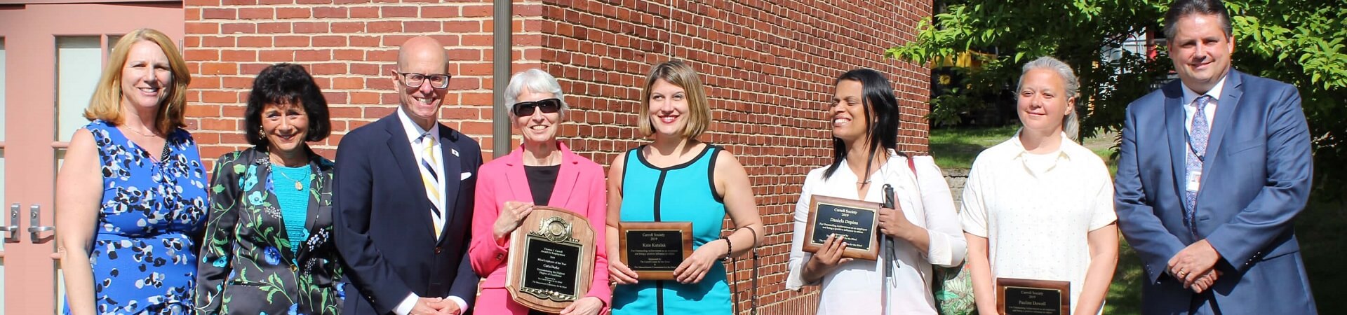 Carroll Society winners from 2019 stand together holding their awards.