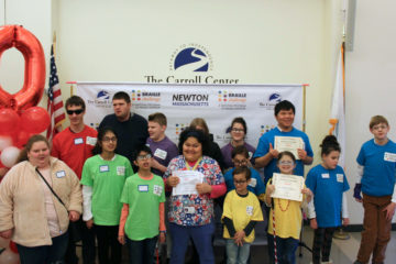 A group of all the braille challenge competitors pose in front of a banner.