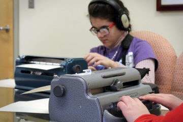 In a classroom, a student adjusts her brailler during the Braille challenge.