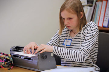 Varsity group winner, Paige Drury, types on her brailler during the Braille Challenge.