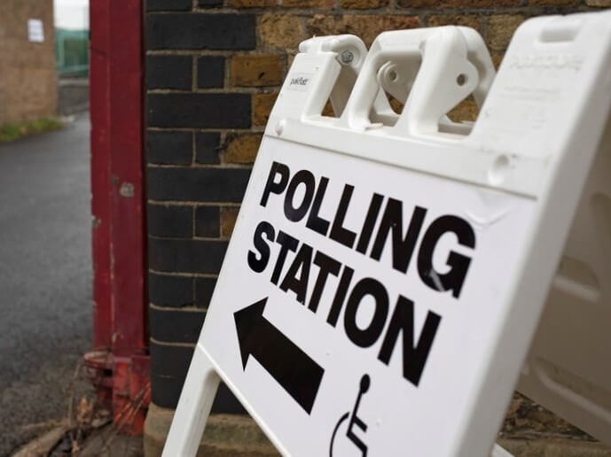 A white sandwich board sign reads "Polling Station" and has an arrow pointing to the left.