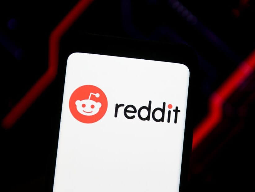 The Reddit logo, featuring a smiling alien with a single antennae on his head, is seen displayed on a smartphone screen.