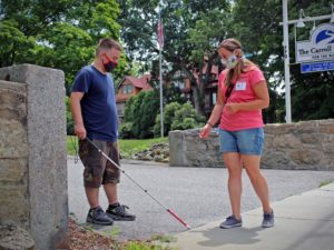 A student in the youth learning day program works on his Orientation & Mobility Skills with a Certified Orientation & Mobility Specialist at the foot of the Carroll Center's driveway.