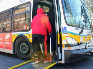 During an MBTA Travel Training accessibility session held in the Carroll Center for the Blind's parking lot, a client steps onto a new 52 bus.