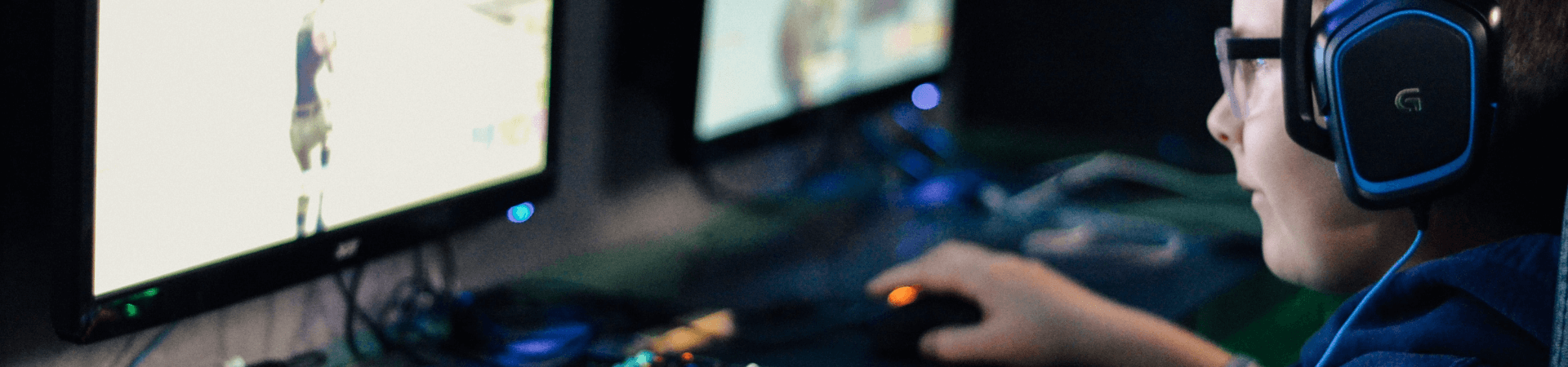 A boy wearing headset gaming on his computer.