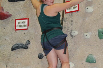 zoomed in picture of a green tank topped girl on a climbing wall