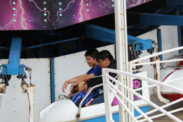 2 teen boys talking on a rollercoaster ride