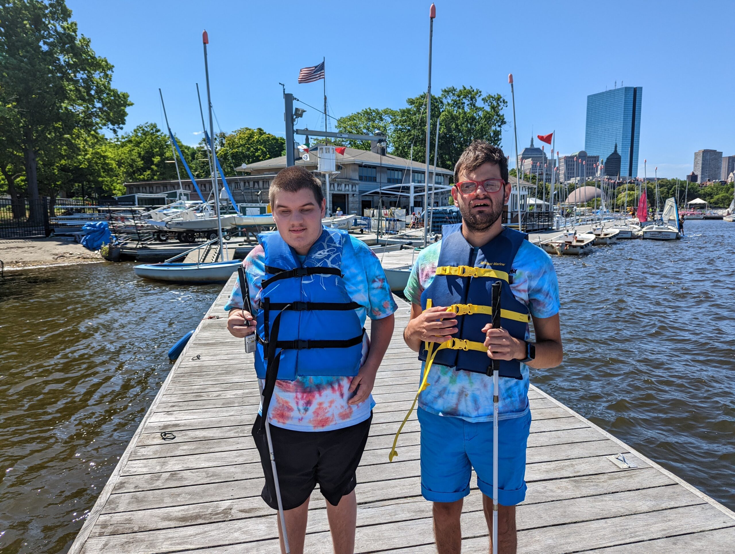 A teenager and supervisor with life vests on in front of the docks