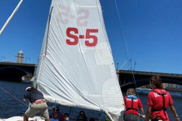 A full shot of a sailboat with 5 individuals getting in