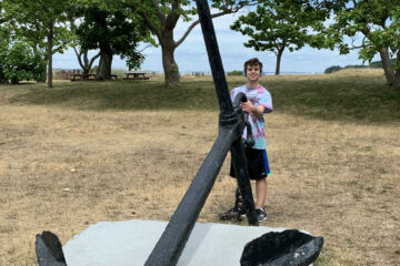 A teen wearing a tie dye shirt holding a giant anchor
