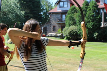 A teen girl with a striped shirt shooting a bow