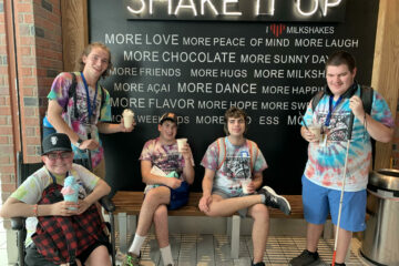 4 Carroll teens in tie dye shirts and a supervisor all eating milkshakes