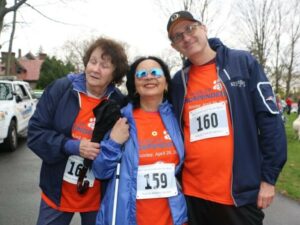 Three participants wearing matching orange shirts pose together at a past Walk for Independence.