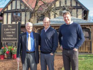 The Gund family poses beside a sign at their newly dedicated building at the Carroll Center for the Blind.
