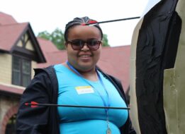 During her time in the Carroll Center's summer program, Lirianni German smiles as she collects her arrows from the target during Archery.