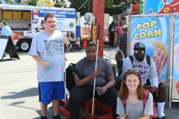 3 smiling Carroll Center summer program students and an instructor posing at the Waltham Lions Carnival