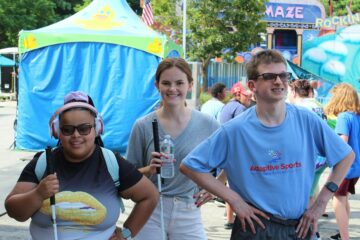 2 smiling Carroll Center summer program students and an instructor posing at the Waltham Lions Carnival