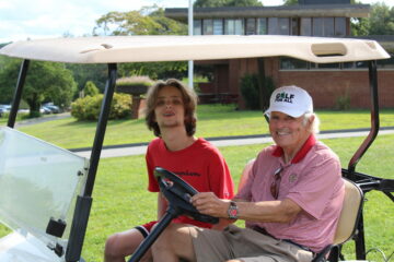 A USBGA coach and student smiling in the golf cart
