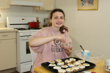 a student putting sprinkles on cupcakes she made in a baking class