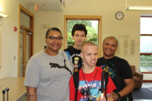 A summer program participant smiling for a picture on campus with his family