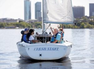 4 SailBlind sailors smiling and talking to each other on a boat