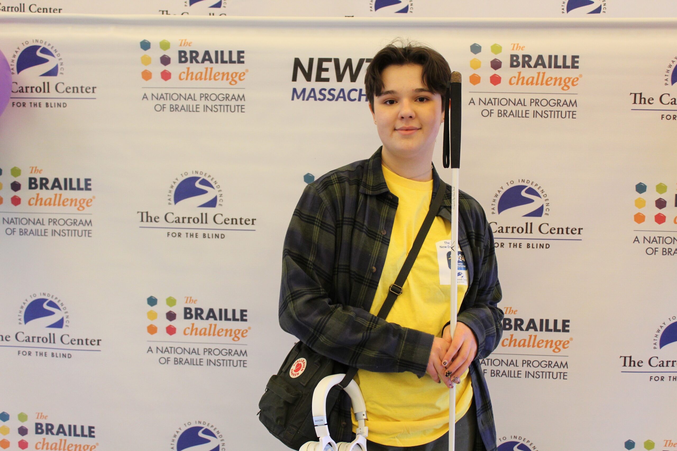 Braille Challenge participant smiling for a photo in front of the Carroll Center Braille Challenge backdrop