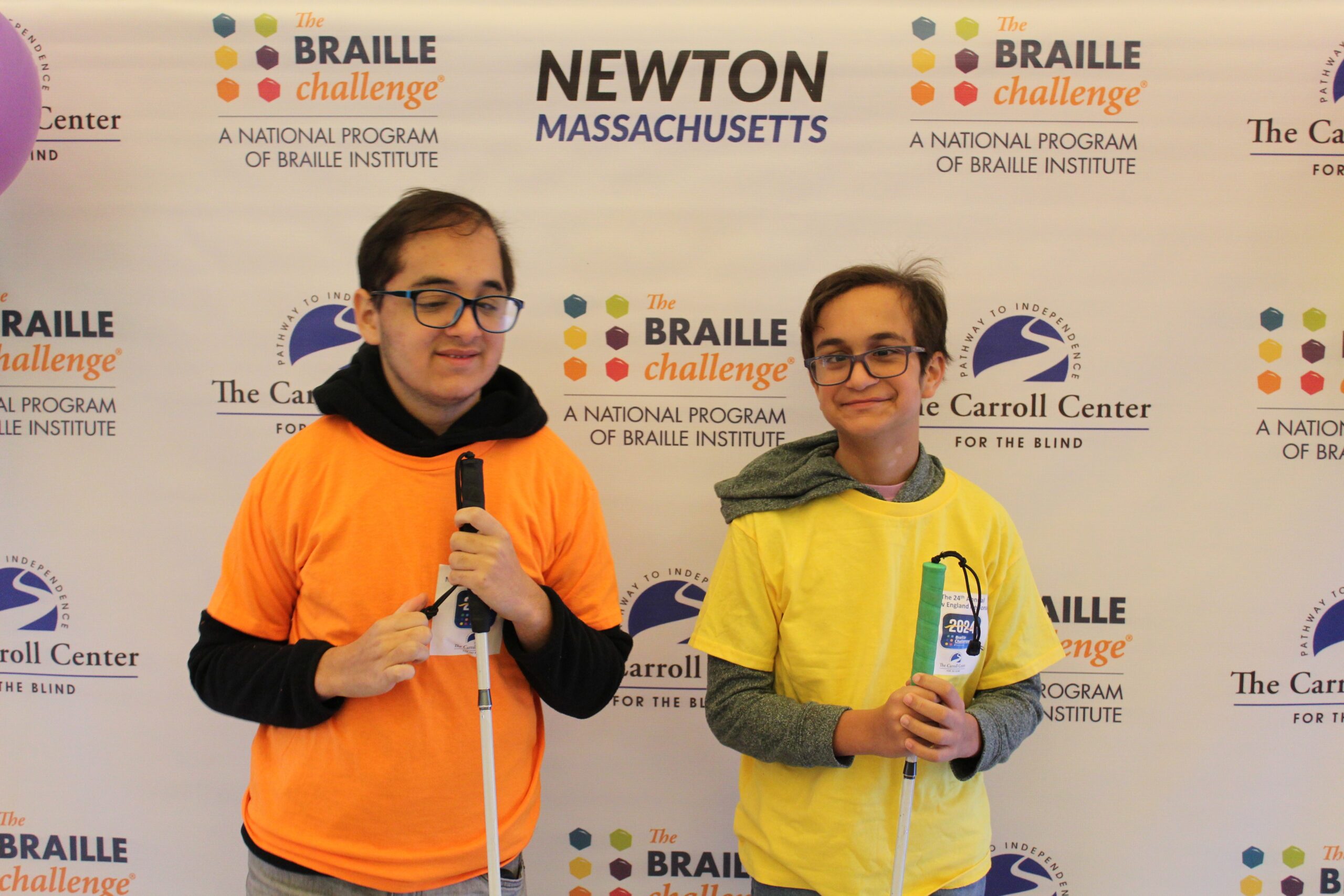 2 Braille Challenge participants smiling for a photo in front of the Carroll Center Braille Challenge backdrop
