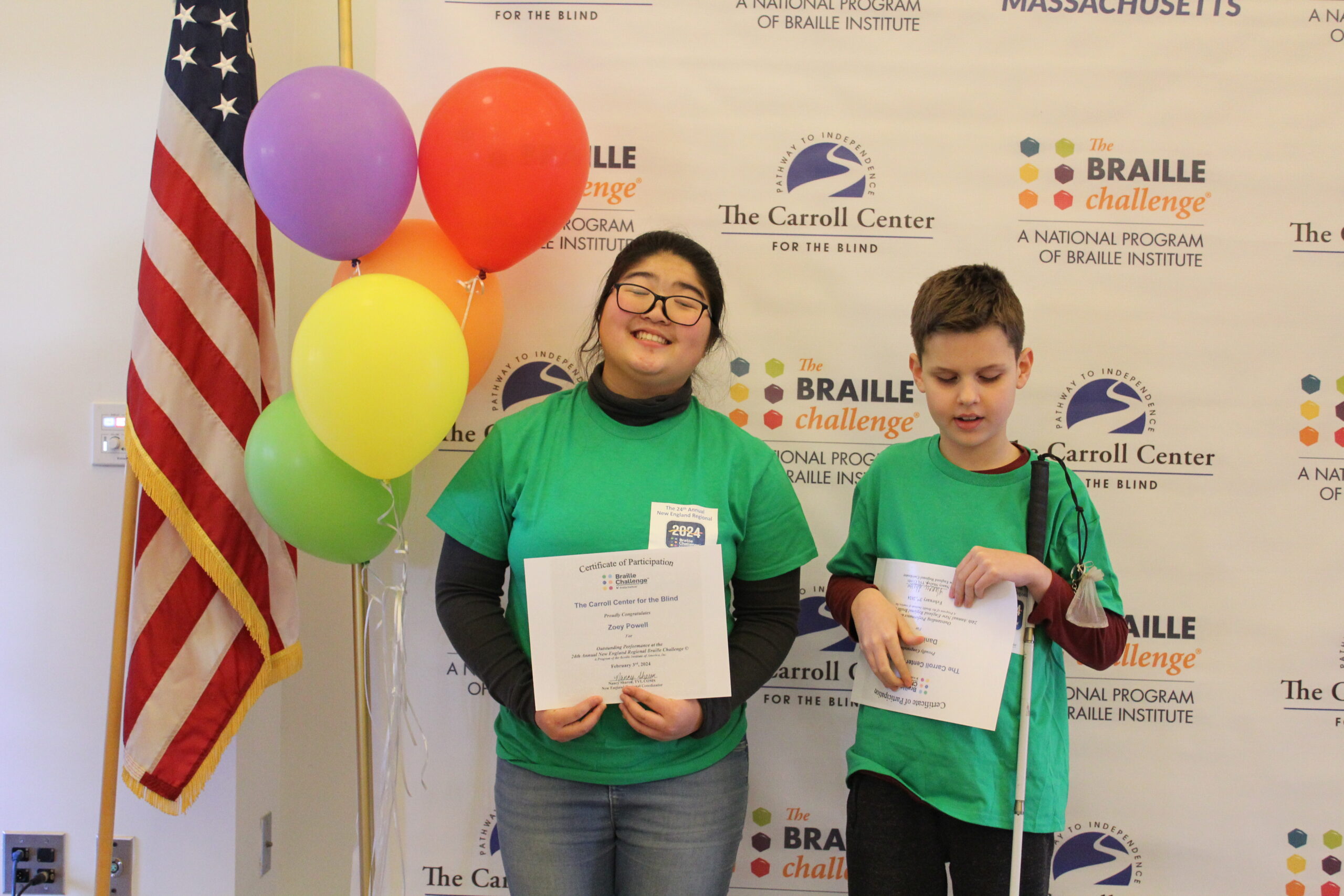 2 Braille Challenge participants smiling for a photo with certificates in front of the Carroll Center Braille Challenge backdrop