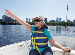 An older blind woman smiles as she steers a sailboat.