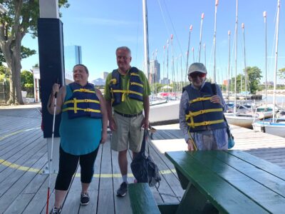 Three SailBlind sailors standing on the dock and smiling.