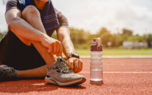 A man preparing for jogging on the running track around the football field.