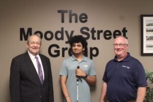 Real World of Work Experience Intern standing in between to staff members from the Moody Street Group. The Moody Street Group logo is behind them.