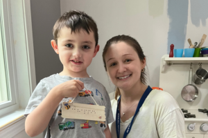 TVI and student Young boy holding a braille craft project with their TVI.
