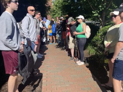 photo of 20 plus sailors and volunteers standing on brick pavement outside the entrance of the Whitney Hotel.