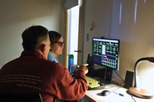 An assistive technology instructor points at computer screen that client is working on.
