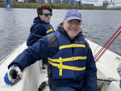 Photo of sighted guide, John, inside a sailboat smiling at the camera