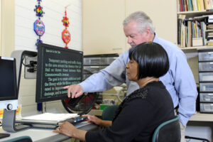 Low Vision Therapist is helping a client who is using a magnifier device.
