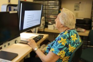 Client is using a magnifier device to read a paper in Low Vision Clinic.